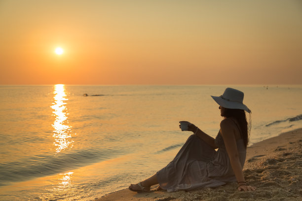 年轻女子喜欢早上在海滩上喝咖啡图片下载