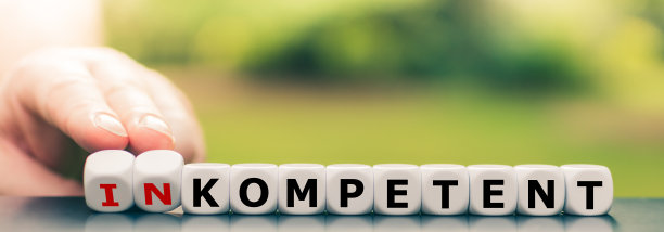 手转动骰子，改变德语单词“inompetent”(“无能”)到“kompetent”(“称职”)。图片下载