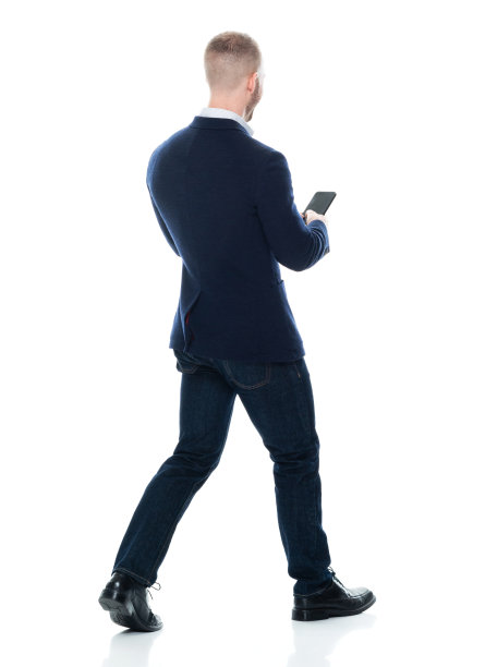 白人年轻男性商务人士走在白色背景前，穿着商务休闲装，使用智能手机图片下载