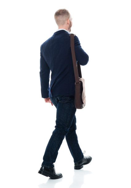 白种年轻男性商务人士走在白色背景的前面，背着背包和提包图片下载