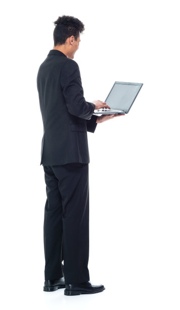 非洲裔男性商务人士穿着商务休闲装，使用笔记本电脑站在白色背景前图片下载