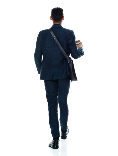 非裔美籍年轻男性商人戴着背包，拿着咖啡杯走在白人背景前图片下载