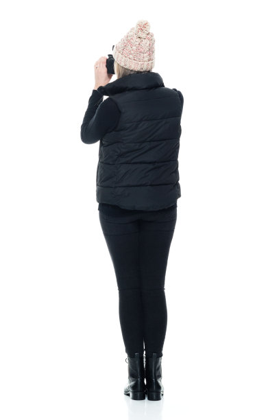 白人女摄影师穿着马甲站在白色背景前，拿着相机图片下载