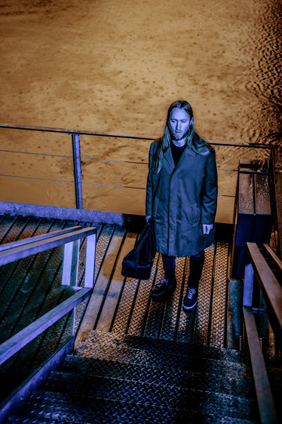 肖像绝望的成年男子在风衣携带一个袋子站在楼梯前在夜间存货照片图片下载