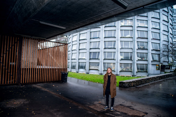 成年男子在风衣站在黑暗的地下通道在雨天-库存照片图片下载