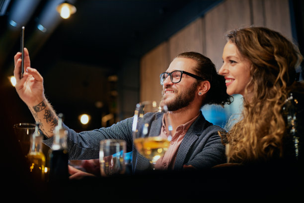 可爱的白人时尚夫妇坐在餐厅吃饭和自拍。图片下载