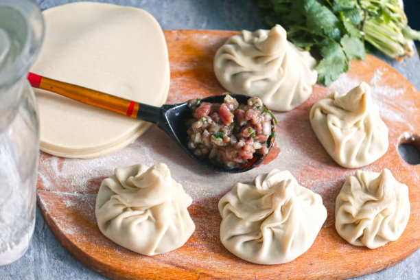 格鲁吉亚饺子与香菜，香菜在厨房板上的特写照片与人的手图片下载