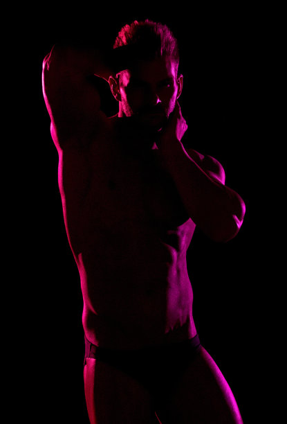 白人年轻男性穿着男性内裤站在黑人背景前图片下载