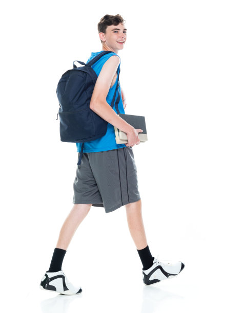 白人大学生背着背包，拿着课本，用运动球在白人背景前行走图片下载