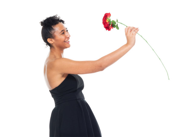 非洲裔女性穿着连衣裙，手持一朵花站在白色背景前图片下载