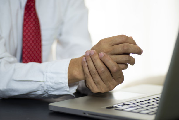 商人痛苦的手，而工作与笔记本电脑。图片下载