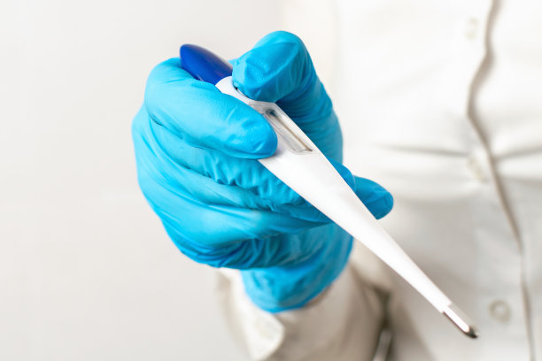 蓝手套中的医生手持电子温度计，浅色背景特写。高温、病毒感染或疾病症状，诊所的健康控制图片下载