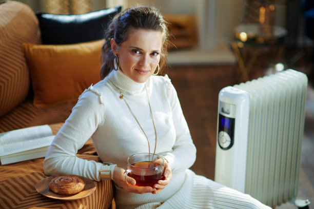 优雅的女人和暖气片与茶杯和小圆面包图片下载