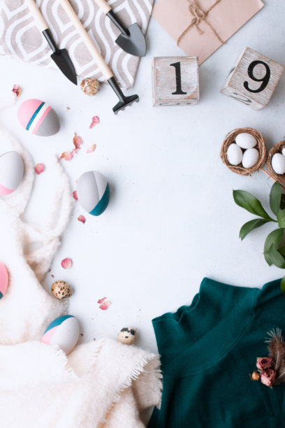 复活节快乐。鹌鹑蛋，彩色蛋和花园用品放在一张白色的桌子上。春天的概念。图片下载