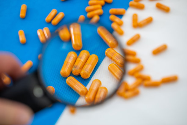 放大镜显示在白蓝色背景上一些橙色药丸的放大图片下载