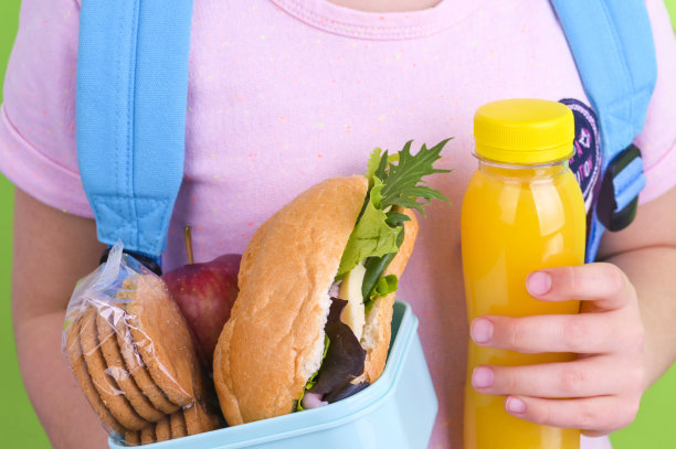 粉色连衣裙小女孩手拿午餐盒和果汁，背着书包图片下载