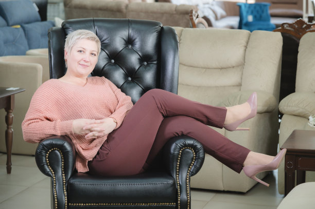 中年妇女的肖像。这家家具公司的老板兼董事正微笑地坐在一张昂贵的黑色皮革扶手椅上。捷径坚强的女性图片下载