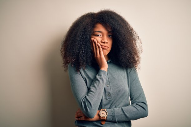 年轻美丽的非洲裔美国女人与非洲式的头发站在孤立的背景思考看起来疲倦和厌倦的抑郁症问题交叉双臂。图片下载