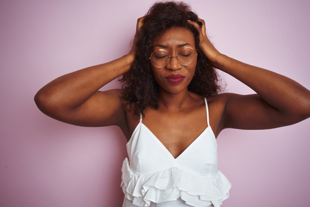 年轻的非洲裔美国妇女戴着眼镜站在孤立的粉红色背景下忍受着头痛绝望和压力因为疼痛和偏头痛。手放在头上。图片下载