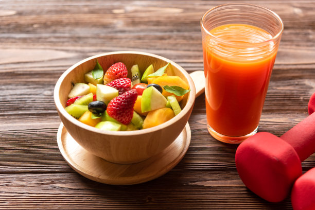 女性健康生活方式饮食，包括鲜榨橙汁、水果沙拉和哑铃运动器材图片下载