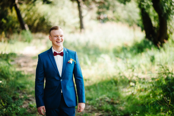 公园里的快乐男人。穿西装打领结的新郎。新郎身着燕尾服微笑着等待新娘。婚礼当天是富有的新郎。图片下载
