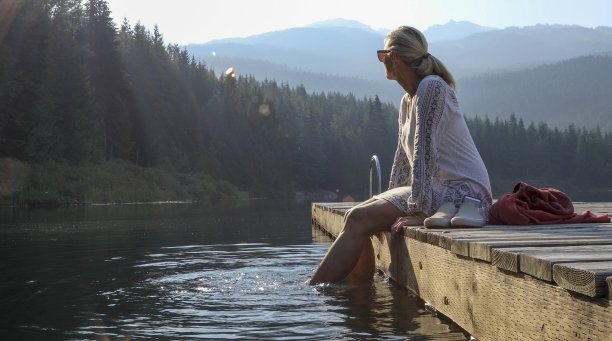 成熟的女人在木栈桥上休息，眺望湖面图片下载