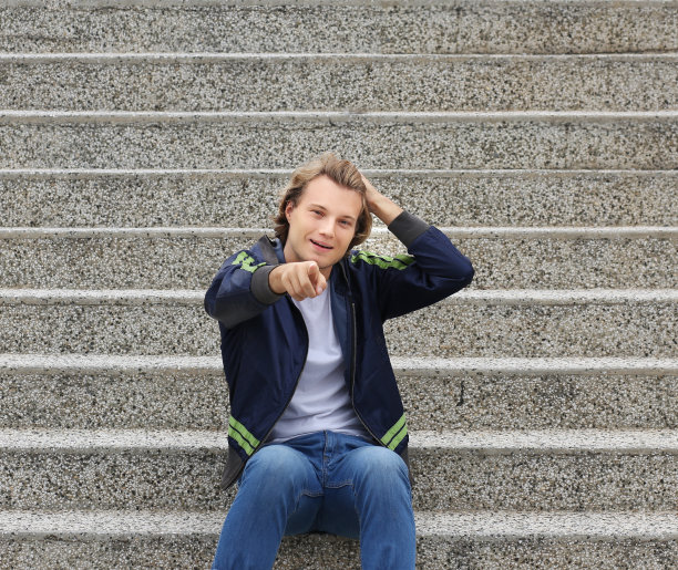 都市背景中迷人的青少年男孩指向镜头图片下载