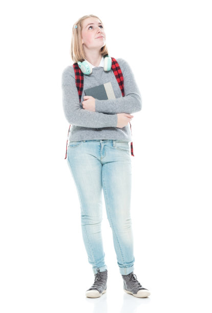 z一代的初中生穿着毛衣，拿着课本，戴着耳机站在白色背景前图片下载