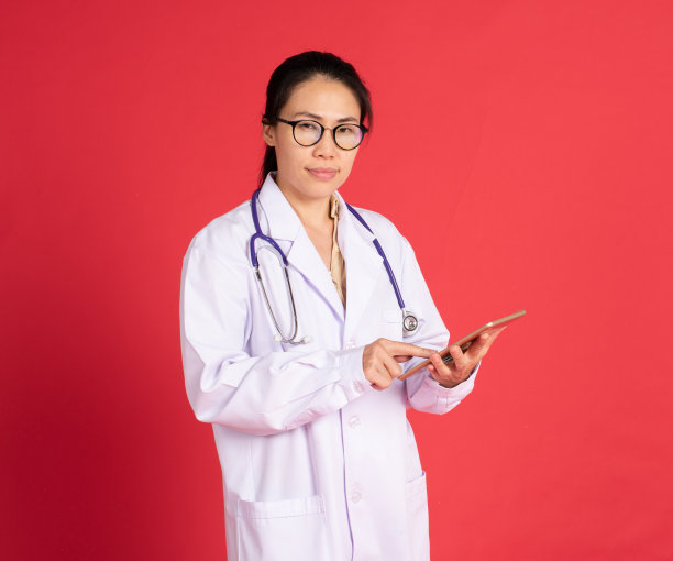 微笑美丽的亚洲年轻女医生的肖像与数字平板孤立在红色的背景图片下载