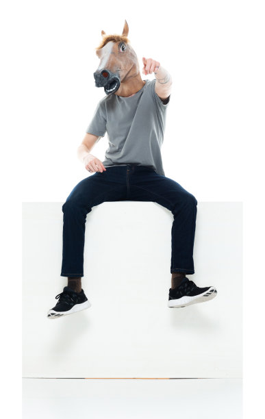 白人年轻男性坐在白色背景前戴面具伪装图片下载