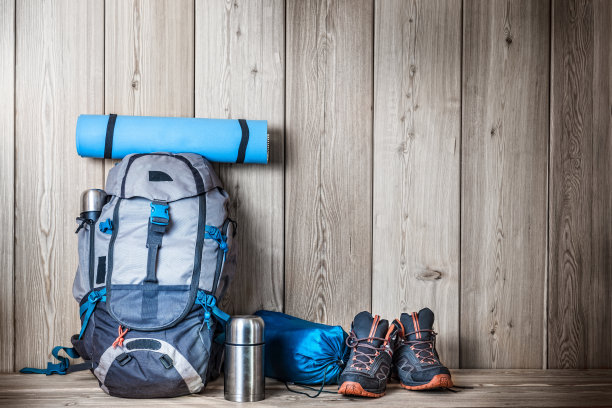 木质背景上的露营装备、鞋子、背包和热水瓶图片下载