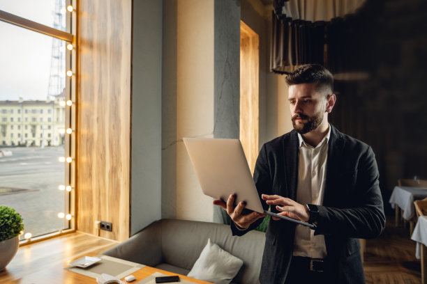 在咖啡馆室内的成年白人络腮胡男子。带有复制空间的生活方式概念照片。用笔记本电脑在窗边工作图片下载