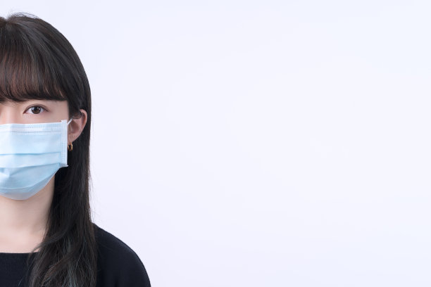 年轻的亚洲妇女肖像，戴着医用外科蓝色面具在黑色条纹布。图片下载