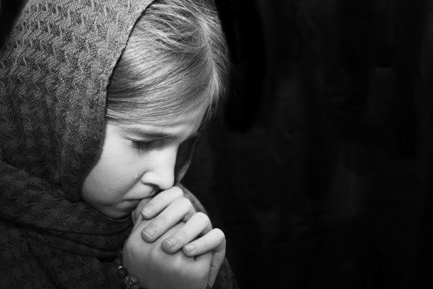 一个拿着手帕，手里拿着念珠的女孩向上帝祈祷并哭泣。黑白照片。忏悔、恳求和悲伤的概念。图片下载