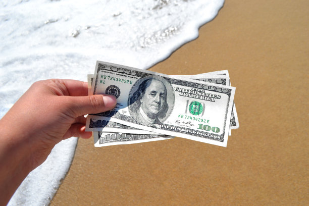 手持300美元钞票，背景为海洋的女孩图片下载