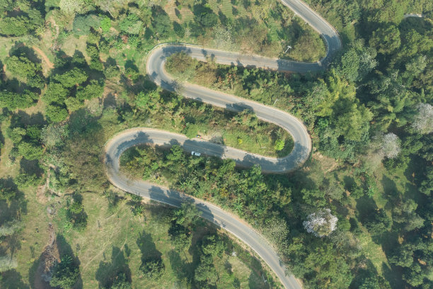 以森林山为背景的沥青蜿蜒道路鸟瞰图。通过无人机安全驾驶和旅行理念，欣赏陡峭弯道的风景。图片下载