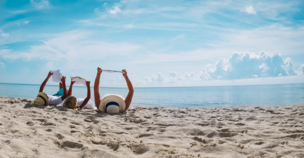 母亲和孩子在海滩读书，家庭度假图片下载