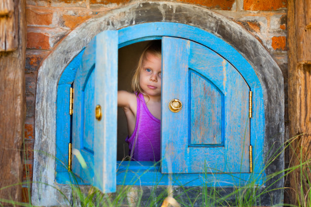 快乐的孩子从玩具屋的窗户往外看图片下载