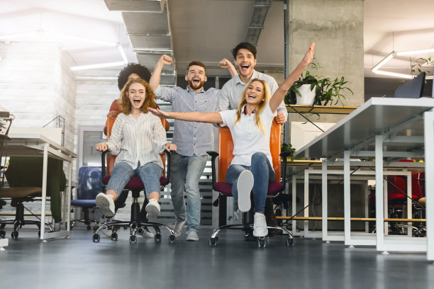 快乐的同事在办公室里玩得开心，让椅子赛跑图片下载