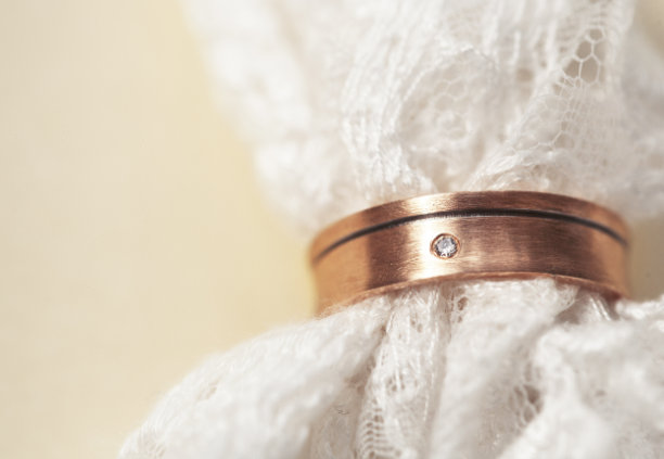 金色结婚戒指的精美微距照片，黄色背景上带有蕾丝特写图片下载