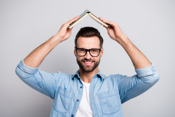 照片有趣的英俊的家伙抱着绿色最喜欢的书在头积极的孩子的情绪情绪穿眼镜休闲牛仔衣服孤立的灰色背景图片下载