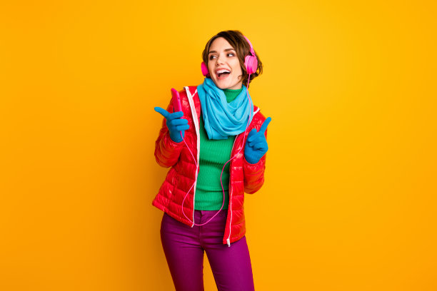 滑稽的女士的照片，拿电话，听耳机，跳舞，激动的聚会，冷的心情，穿休闲的红色外套，蓝色的围巾，手套，裤子孤立的黄色背景图片下载