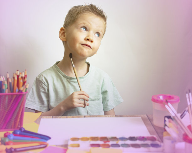 孩子用画笔在纸上画画，学校里的男孩艺术家图片下载