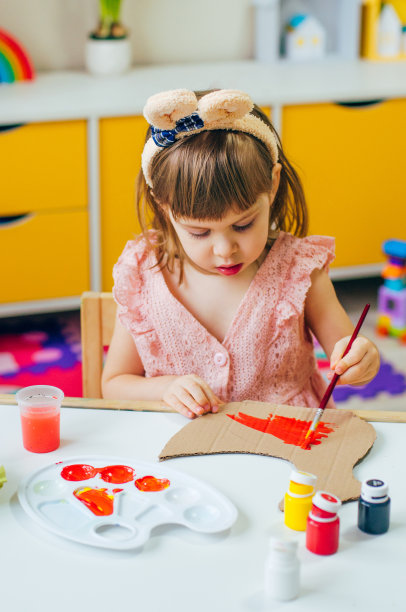 蹒跚学步的小女孩用兔子耳朵画母鸡作为复活节装饰图片下载