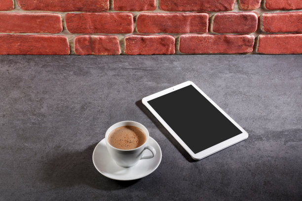 在灰色的石头纹理上，一杯咖啡和一个数码平板电脑(屏幕上有剪切路径)图片下载