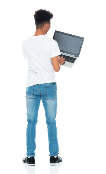 非裔美国男孩穿着牛仔裤站在白色背景下使用电脑图片下载