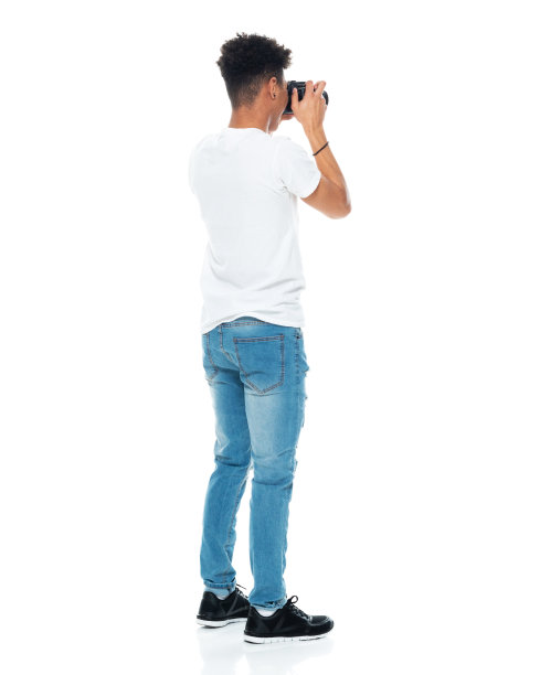 z一代男孩摄影师穿着牛仔裤拿着相机站在白色背景前图片下载