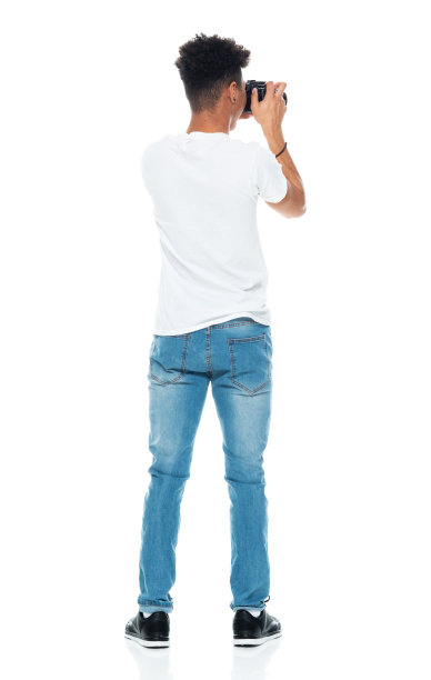 非裔美国男孩穿着牛仔裤拿着相机站在白色背景前图片下载