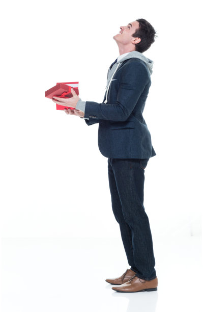 白人男性商务人士在白色背景的办公室穿着运动衫，拿着礼盒图片下载