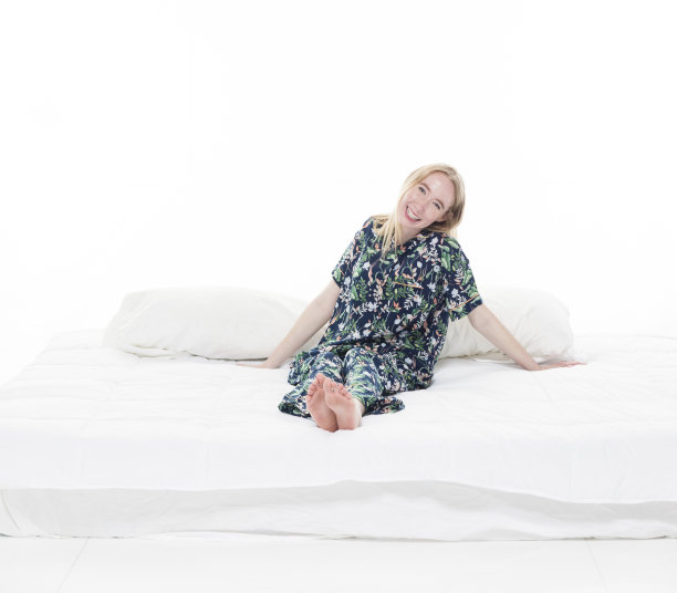 白人年轻女性穿着睡衣在白色背景的卧室里图片下载